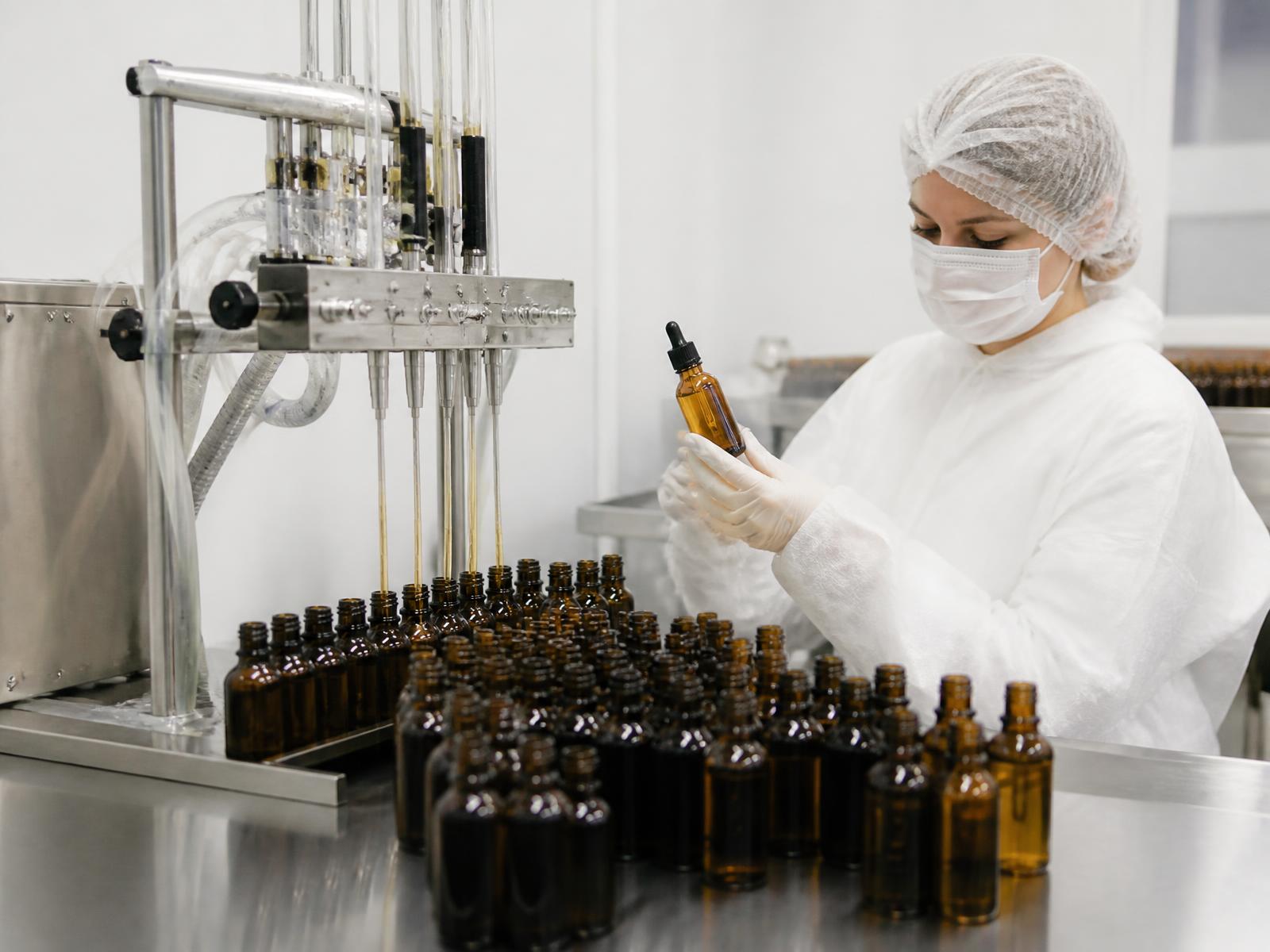 Amber dropper bottles being filled and inspected on the packaging line at the El Guarco laboratory.